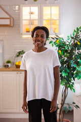 Fototapeta premium African american woman in white t-shirt in the kitchen. Mock-up.