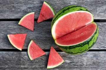 Seedles watermelon and slices on wooden background.