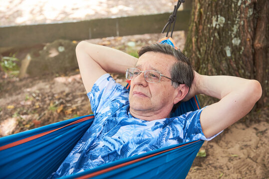 Hispanic Senior Thoughtful Man Lying In A Blue Hammock.