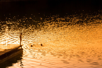 coucher de soleil au bord d'un lac avec des nageurs en été