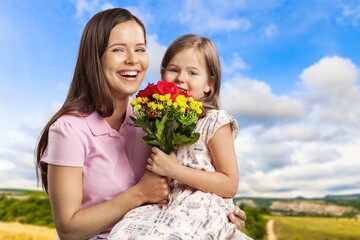 Little daughter congratulating mom with Mother's day at home and giving her fresh flower bouquet
