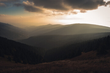 Naklejka na ściany i meble Landscape of warm light sun rays on sky through the clouds over the mountains in Czech republic, Jeseniky