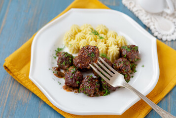 Swedish meatballs with mashed potatoes on white plate. Close up with meatball on a fork. Selective focus, horizontal.