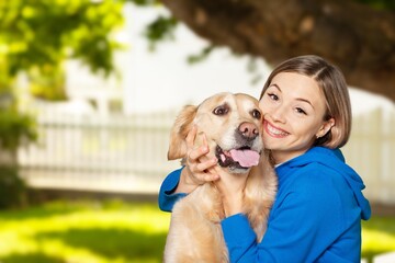 Teen girl hugging dog at the nature and smiling. Pretty young female with doggy pet in the sunny field