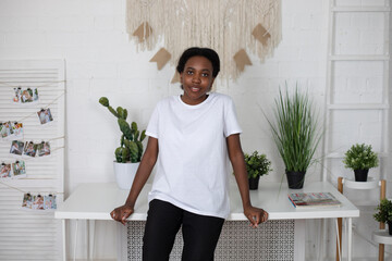 African american woman in white blank t-shirt at home.. Mock-up.