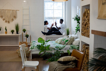 Couple sitting opposite each other on the windowsill at home.