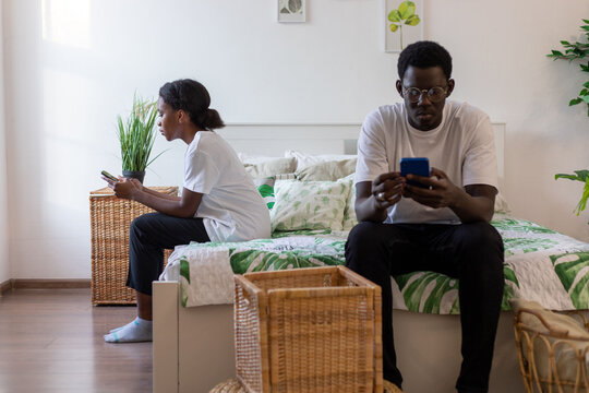 A Couple Of African Americans Sit Facing Away From Each Other And Look At Their Phones.