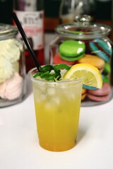 Yellow lemonade with ice on the background of dessert