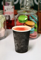 Coffee with cream and strawberries on the background of desserts, on the bar counter