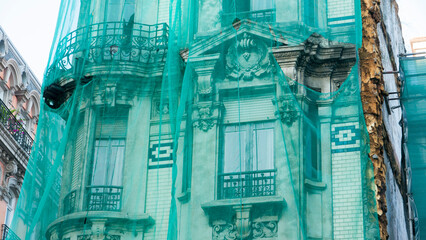 Edificio antiguo de centro histórico cubierto con una lona verde de reformas