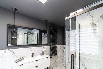 Modern flat bathroom with grey walls and white bath and shower cabin