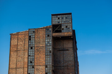 Ruins of an abandoned industrial plant. Brick walls against the background of the blue sky. Photo taken on a sunny day.