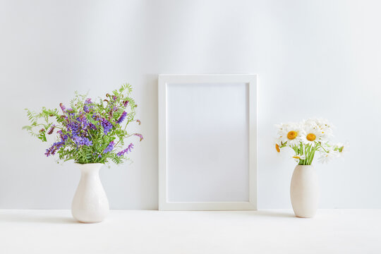 Home interior with decor elements. Mockup with a white frame and wildflowers in a vase on a light background