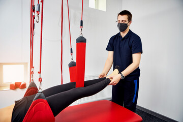 Rehabilitation specialist doing active treatment on suspension straps to female patient. Concept of...