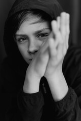 Black and white portrait of teenage boy on dark background. Low key close up shot of a young teen boy. Black and white photography. Selective focus