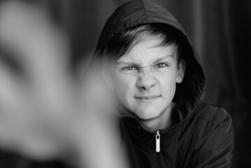 Black and white portrait of teenage boy on dark background. Low key close up shot of a young teen boy. Black and white photography. Selective focus