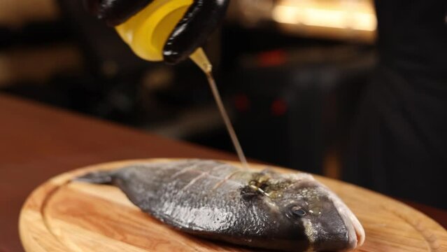 chef in black gloves prepares fish sea bream
