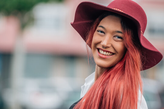portrait of smiling redhead girl in hat outdoors on the street