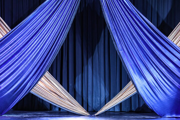 Bright braided front curtains in the blue and silver colors of a stage, in the background another blue curtain.
