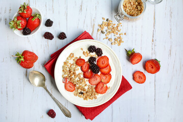 Granola for breakfast with berries and yogurt. Oatmeal or muesli with strawberries and blackberries. The concept of diet, healthy food and eating. View from above