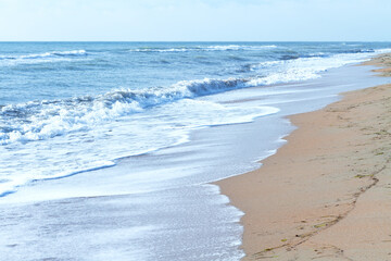 Soft waves with white foam on a deserted beach near the sea. Natural background. Calm calm seascape.