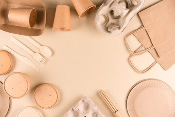 Frame made with paper utensils and wooden cutlery. Kraft paper eco food packaging over light brown...