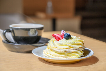 meringue cake with buttercream and fresh strawberries on top. Cupcake dessert and coffee in cafe.