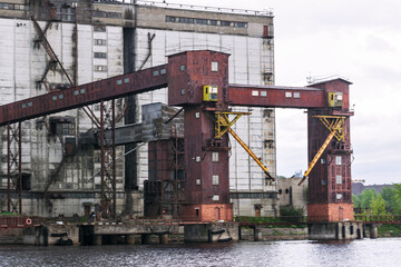 Old abandoned granary elevator and grain bin on the bank of a navigable river.