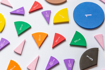 Violet orange yellow pieces of fractions on the table. Close up math material for study. Back to school, geometry lessons, mathematical education for preschooler. Creative study