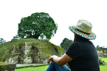 Mujer viajera sentada, observando uno de los templos en las Ruinas de Iximche en Guatemala.