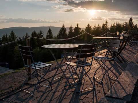 Wooden tables at outdoor restaurant in nature during sunset