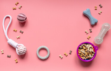 Close up rubber balls, rings, bowl with snacks for pets. Multicolored balls for dogs and bone snacks on a pink background. Toys, balls, bones, for playing and training