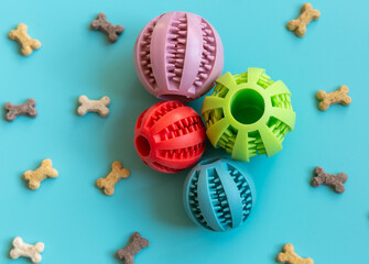 Close up rubber balls for pets. Multicolored balls for dogs and bone snacks on a blue background. Toys, balls, bones, for playing and training