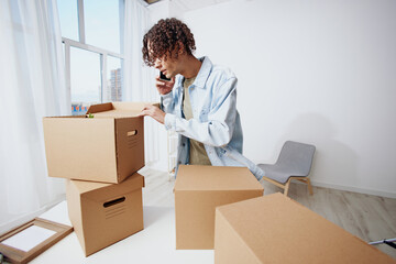 guy with curly hair unpacking things from boxes in the room interior