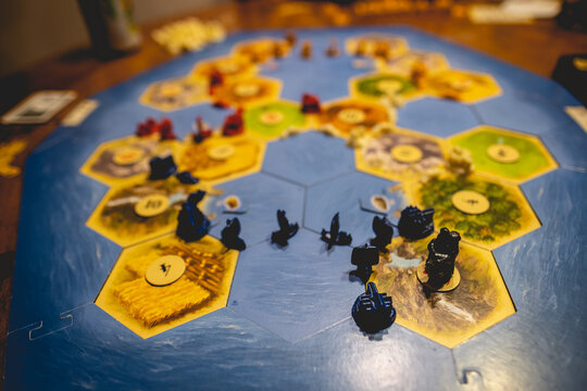 Closeup of  'Catan' board game with 'Seafarers' expansion in a wood table with interior light 