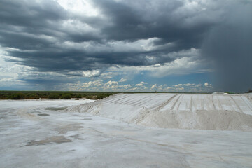 Industrial. View of the natural white salt flats and open cast mining pit under a dramatic sky.