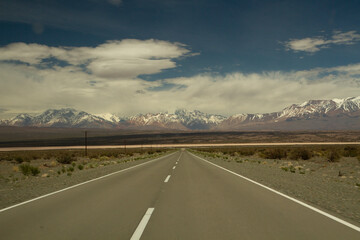 Traveling along the asphalt highway across the arid desert and into the Andes cordillera, under a...