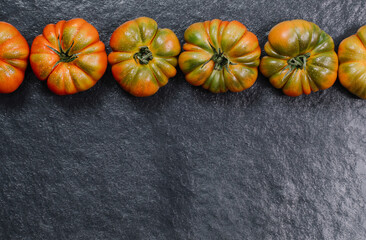 A group of Costoluto big tomatoes on a grey background, rustic concept, space for text