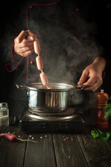 The chef puts sausages in a boiling pot. Cooking delicious breakfast or dinner in the kitchen