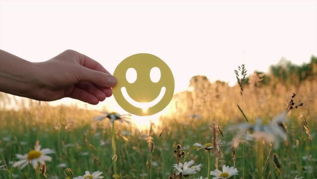 Close up of mother and daughter holding happy face emoticon on background beautiful sunset at calm summer day. Positive picture or cheerful life, World mental health day and eco-friendly concept