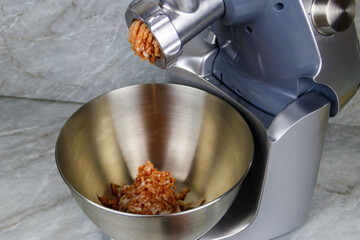 Electric eat grinder with fresh forcemeat on kitchen table. Preparation of minced meat
