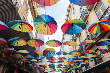 Fototapeta na wymiar Creative lgbt rainbow umbrellas fly on the street. Colorful brightly umbrellas in the city
