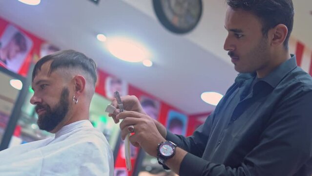 Barber cuts mans hair with straight edge razor 
