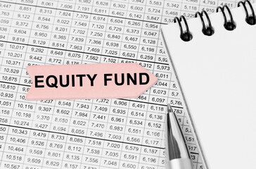 Fototapeta premium On the table among the reports is a notebook, a pen with an arrow with the inscription - EQUITY FUND