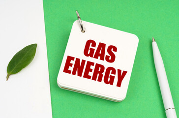 On a white-green surface, a piece of paper, a pen and a notepad with the text - gas energy