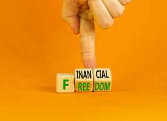 Financial freedom symbol. Concept words Financial freedom on wooden cubes. Businessman hand. Beautiful orange table orange background. Financial freedom and business concept. Copy space.