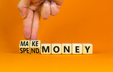 Spend or make money symbol. Businessman turns cubes and changes concept words Spend money to Make money. Beautiful orange table orange background. Business spend or make money concept. Copy space.
