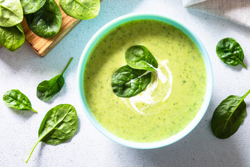 Green spinach cream soup at white table . Healthy vegan dish. Top view .