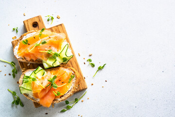 Open sandwich with cream cheese, salmon and cucumber. Top view at white table.