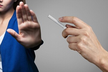 Woman showing stop sign with hand and refusing to take cigarette. No smoking concept